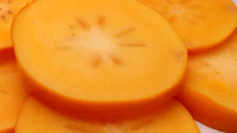 Slices of persimmon, rotating in a circle. Fresh orange persimmon (kaki) Stockbeeldmateriaal 255588062