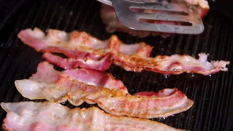 Slices of raw pork bacon is prepared in its own fat. fat bacon strips sizzle. 스톡 동영상 334643149