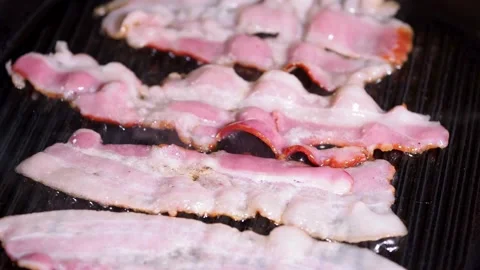 Slices of raw pork bacon is prepared in its own fat. fat bacon strips sizzle. 스톡 동영상 334643179