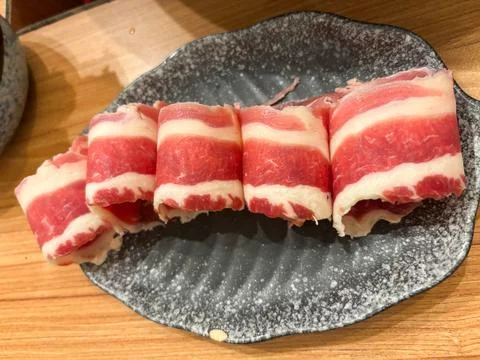 Slices of raw, thinly-shaved beef, beautifully rolled and presented Stock Photos