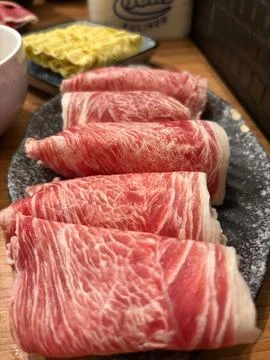 Slices of raw, thinly-shaved beef, beautifully rolled and presented Stock Photos