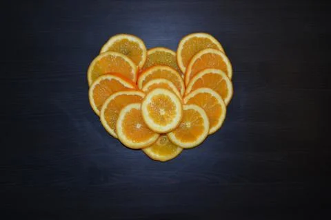 Slices of ripe oranges posed in a shape of a heart. Stock Photos