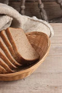 Slices of rye bread and ears of corn in basket Stock Photos