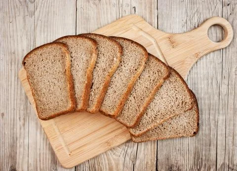 Slices of rye bread and ears of corn on the wooden table Stock Photos