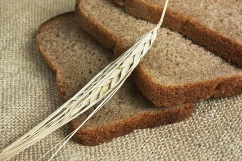 Slices of rye bread and ears of corn on a wooden table 스톡 사진