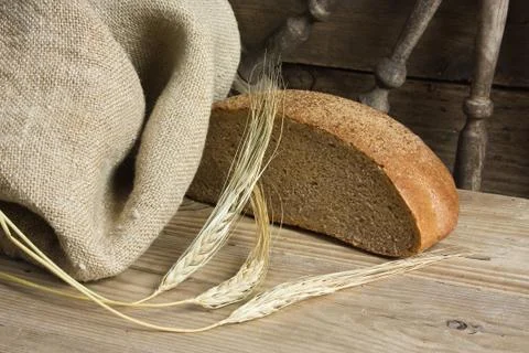 Slices of rye bread and ears of corn on a wooden table Stock Photos