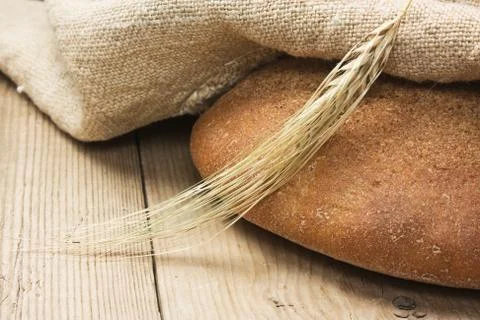 Slices of rye bread and ears of corn on a wooden table Stock Photos