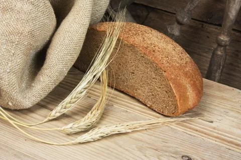 Slices of rye bread and ears of corn on a wooden table Stock Photos