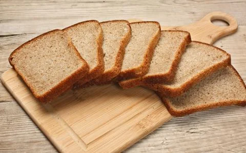 Slices of rye bread and ears of corn on a wooden table Foto stock