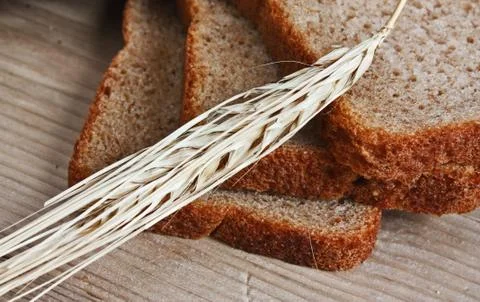 Slices of rye bread and ears of corn on a wooden table Foto stock