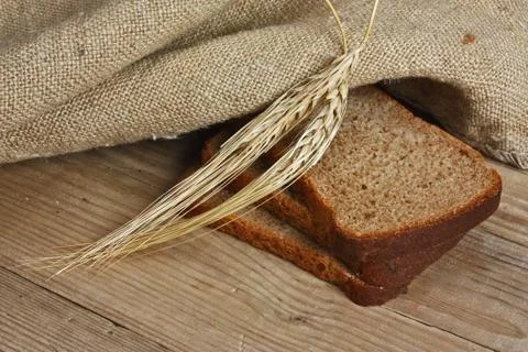 Slices of rye bread and ears of corn on a wooden table Foto stock