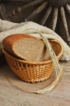 Slices of rye bread and ears of corn on a wooden table Stock Photos