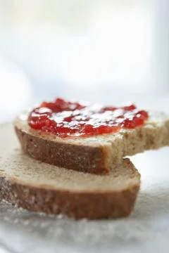 Slices of rye bread spread with jam with a bite taken out Foto stock