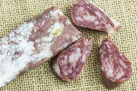 Slices of saucisson on a burlap background Stock Photos