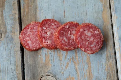 Slices of sausage on a rustic table. Stock Photos