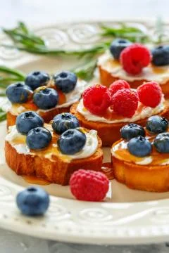 Slices of toasted bread with soft cheese and berries. Stock Photos