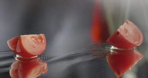 Slices of tomato slide on a mirror surface Video stock 198147190