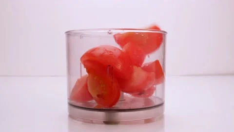 Slices of tomatoes fall into the blender. The mixer turns on and grinds Stock Footage 152192629