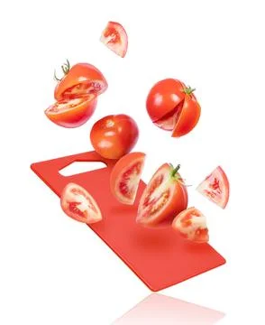 Slices of tomatoes fall on the kitchen board isolated on white background Stock Photos