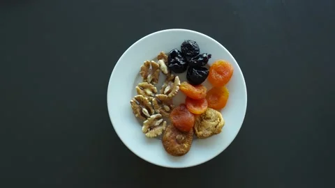 Slices of various nuts, dried apricots and prunes. View from above. White spi Video stock 155148174