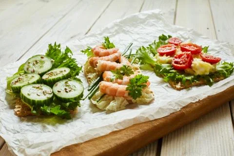 Slices of waffle bread with different vegetables, shrimp and seasoning Stock Photos