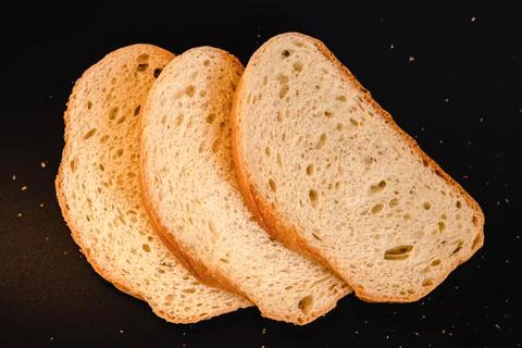 Slices of white bread close up on a black background. rough dappled textured  Stock Photos