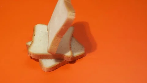 Slices of white bread falling on orange background. 库存影片 143927665