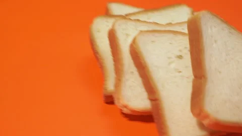 Slices of white bread falling on orange background. 库存影片 143927667
