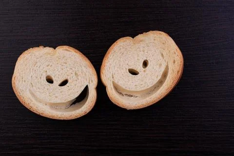 Slices of white bread with holes in the shape of eyes and a smile. Stock Photos