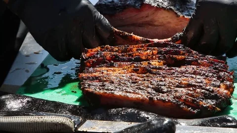 Slicing off and neatly stacking cuts of brisket for a BBQ cook-off Stock Footage 116881354