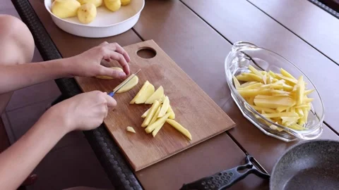 Slicing and preparing fresh potatoes for a delicious meal preparation outdoors Stock Footage 297359447