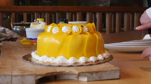 Slicing and serving a mango cake Stock Footage 50025814