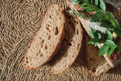Slicing artisan bread on a straw lining, top view. Pieces of fresh homemade.. Stock Photos