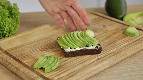 Slicing avocado for toast into small chunks on a bamboo cutting board. Stock Footage 150788241