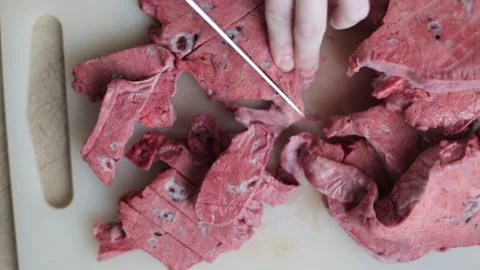 Slicing a beef lung with a knife on a white board. Cynologist prepares treats Stock-Footage 240082828