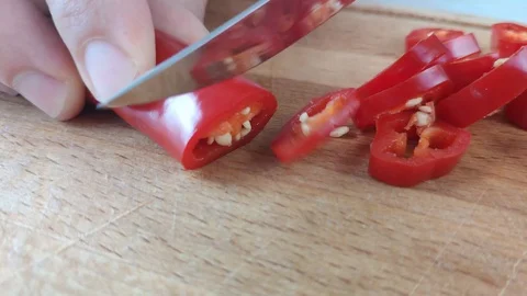 Slicing bitter red peppers with a knife on a wooden Board Stock Footage 129661336
