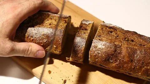 Slicing black long bread with a knife Stock Footage 148040353