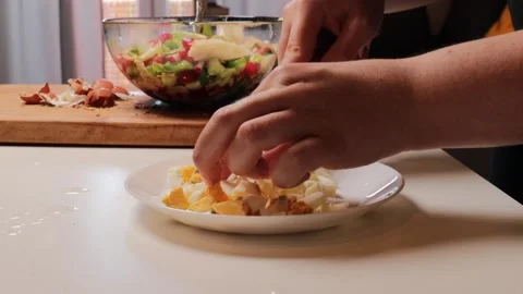 Slicing boiled egg on white plate next to bowl of fresh salad in home kitchen. Stock Footage 316472385