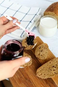 Slicing bread with berry jam and milk on wooden table Stock Photos