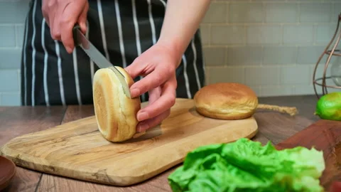 Slicing a bread bun in two for a burger in 4K. Video stock 153729689