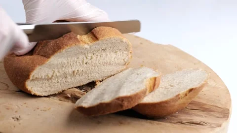 Slicing bread on a wooden background. Stock Footage 150186836
