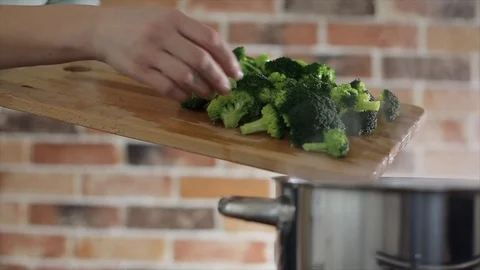 Slicing broccoli on cutting board putting into boilin water Stock Footage 102704489