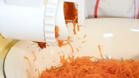 Slicing carrots in a kitchen electric grinder. Video stock 99725375