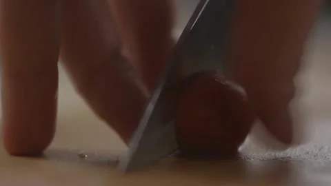 Slicing cherry tomatoes in half with a knife on a chopping board Stock Footage 194478611