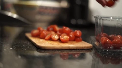 Slicing cherry tomatoes with a kitchen knife on a wooden plate Stock Footage 75352115