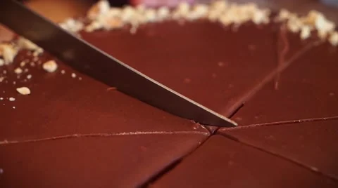Slicing the chocolate cake with the sharp knife. Almonds on the edge Stock Footage 67882048
