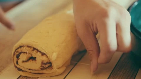Slicing cinnamon roll dough with dental floss close up, cutting sweet pastry Stock Footage 338039633