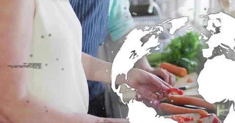 Slicing couple preparing veg at kitchen counter with board carrots apron map Fotos Stock
