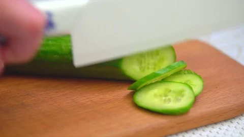Slicing cucumber with a white ceramic knife Stock Footage 75566648
