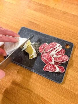 Slicing Cured Sausage on a Cutting Board for a Charcuterie Platter Preparation Stock Photos